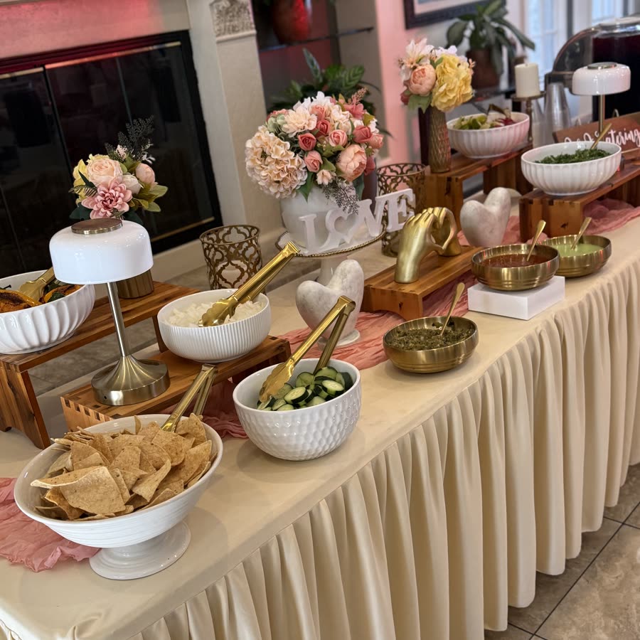 An indoor buffet dressed in blush and gold with brass serving pieces.