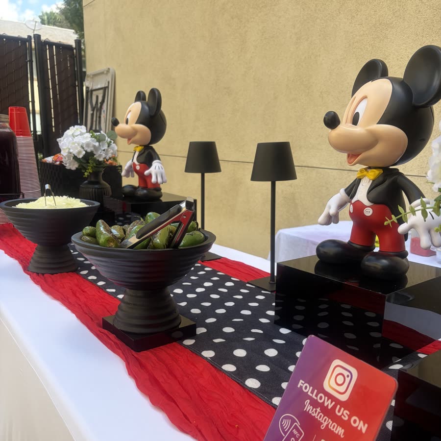 A Mickey themed party table set for children in red, black and white, with a Mickey figure at the center.