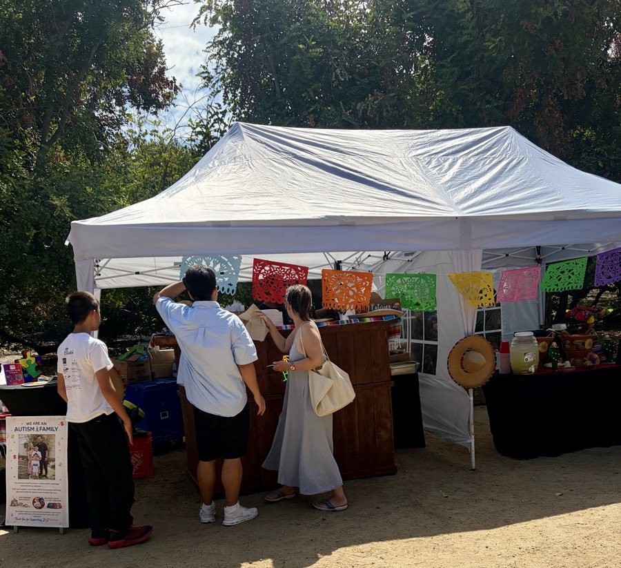 Families gathered under a white canopy at an outdoor event.