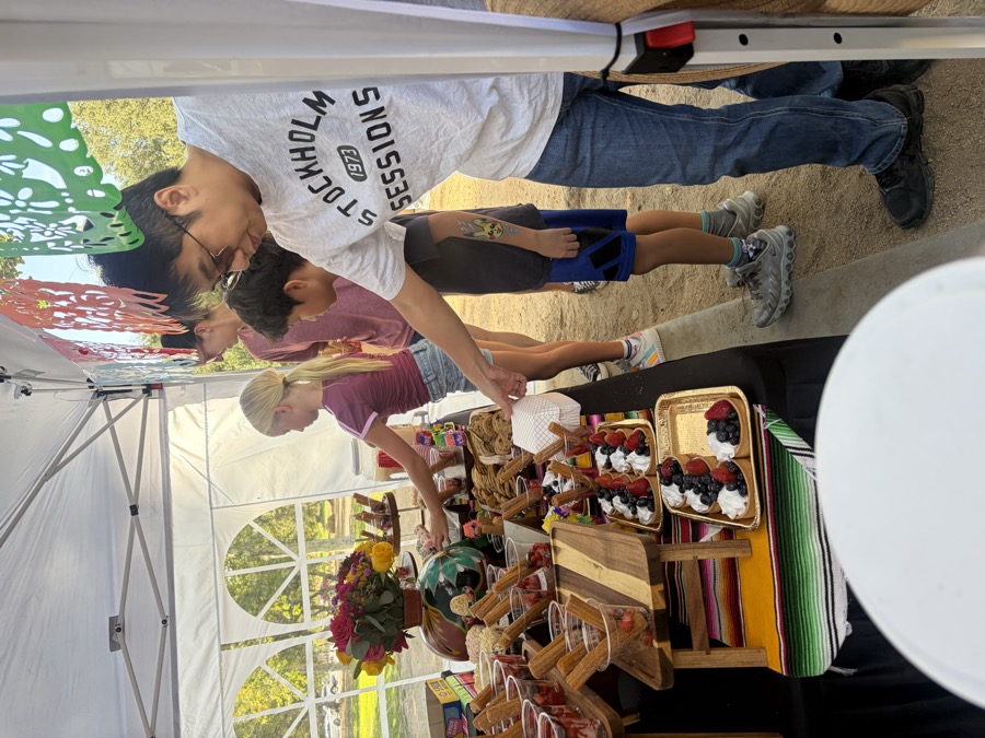 A member of the family serving food at a booth in a J and J shirt.